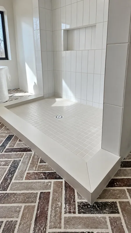 White shower beside a patterned tile floor