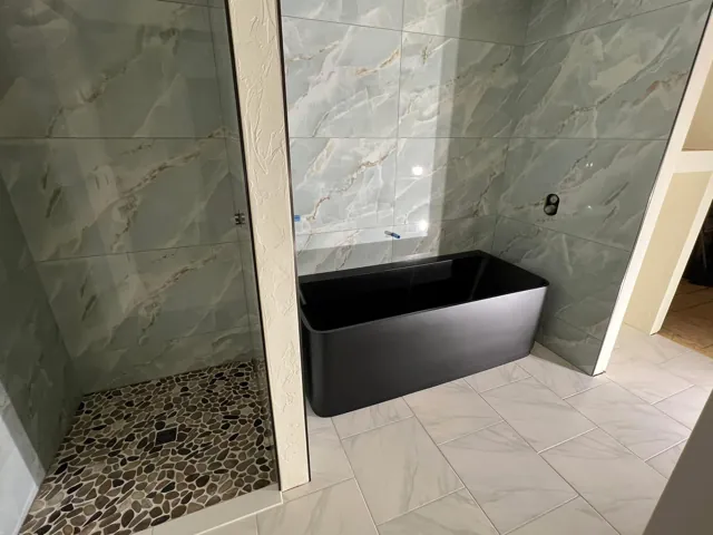Large bathroom wall tile beside a bathtub and pebble shower floor