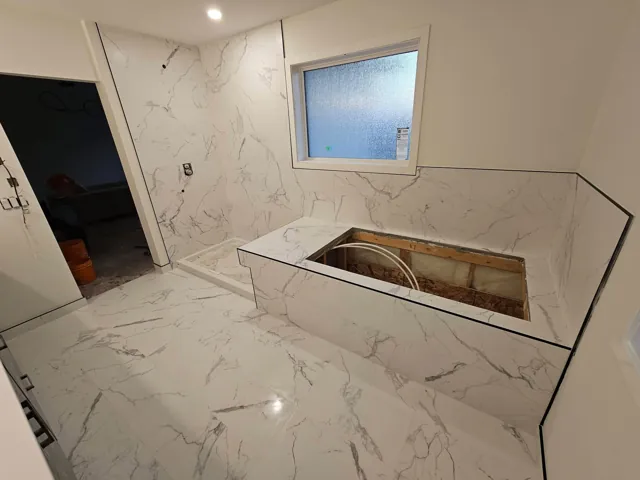 Marble-look bathroom tile around a tub opening during installation