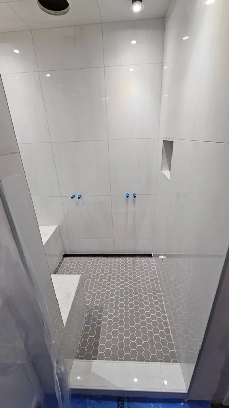 White tiled shower with a niche and bench